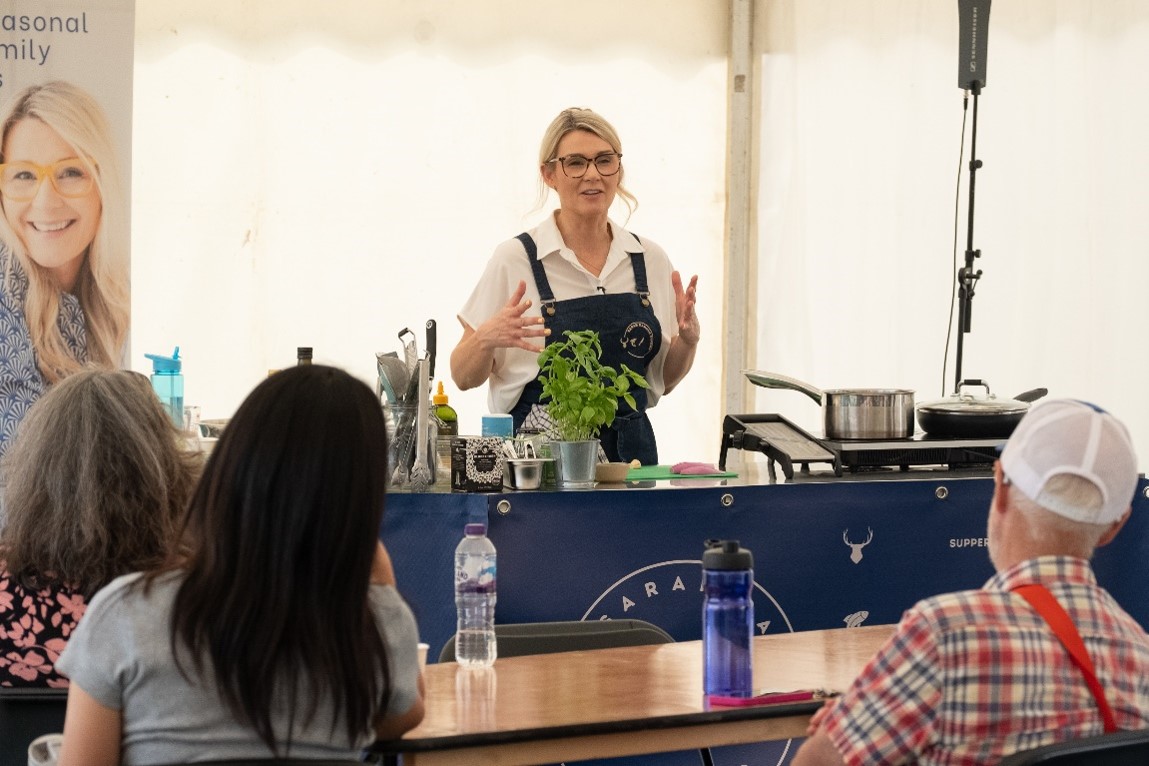 Sarah Rankin standing at cooker demo desk 